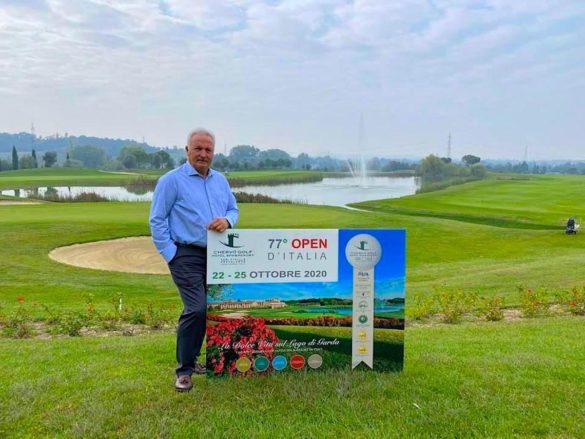 Nella foto, Pietro Apicella con uno dei cartelli dell'Open d'Italia numero 77, davanti al lago che rappresenta l'ostacolo d'acqua vicino al green delle buche finali sui percorsi Giallo e Rosso di Chervò San Vigilio